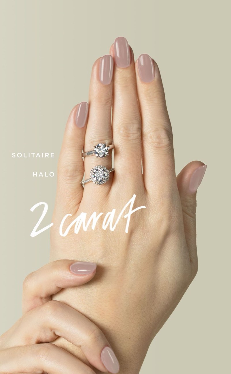 A 2 carat round solitaire ring and a 2 carat round halo ring worn together on one finger